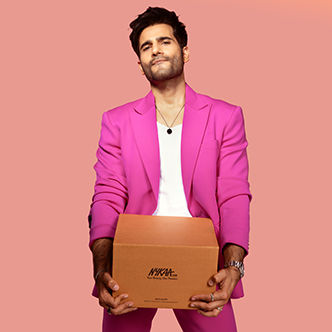 Karan Tacker in pink holding a Nykaa box