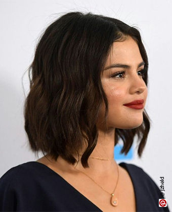 Selena Gomez with wavy hair with a graduated bob
            