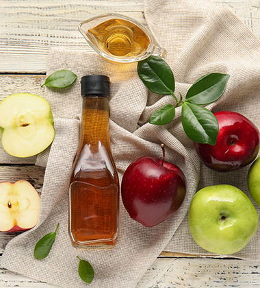  an apple cider vinegar bottle placed next to apples