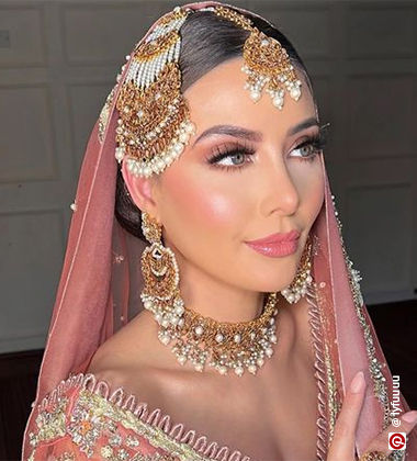 Woman in a pink lehenga with soft pink makeup