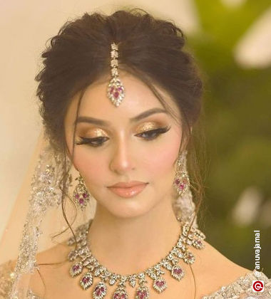 Woman wearing a diamond maang tikka and lehenga with golden eye lids