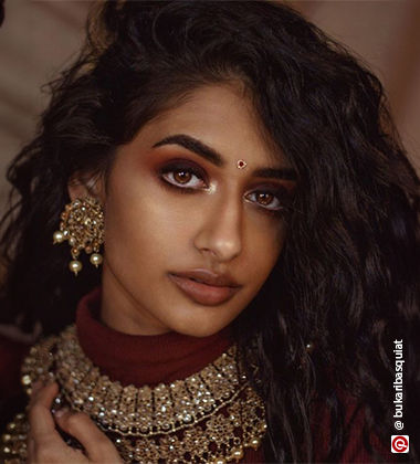 Woman with a side parting and wearing a golden jhummka