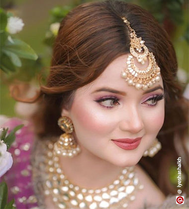 a top angle picture of a woman wearing pink lehenga and surrounded by plants