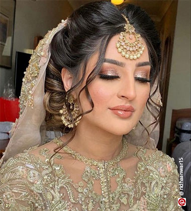 woman wearing a heavily embroidered golden outfit and with sparkly eyeshadow