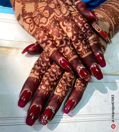 Red coloured nails with mehendi hands