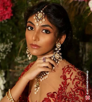 woman playing with her earring wearing a red lehenga