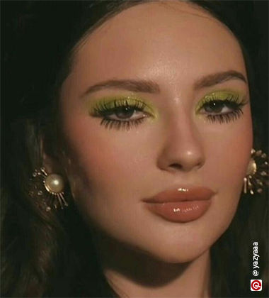 Woman wearing golden earrings and green eyeshadow
