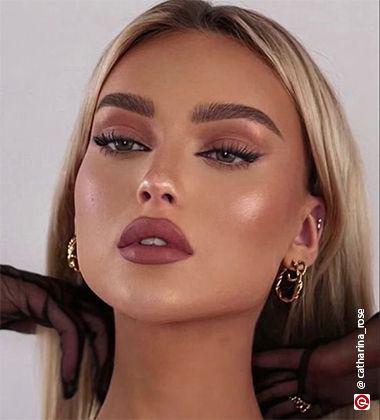 woman putting her blonde hair back wearing golden earrings and brown makeup