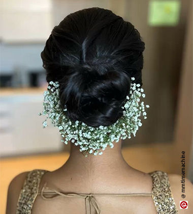 woman wearing a low bun with semi-flowers around the bun