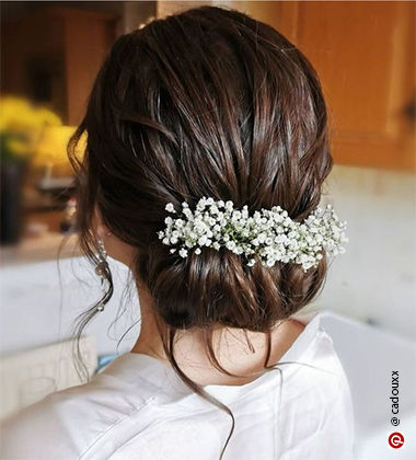 side profile of a woman with delicate white flowers around her bun