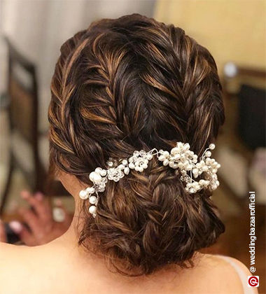 woman with plaited hair strands into a bun with flowers in them