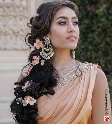 woman wearing a peach-coloured saree and golden earrings